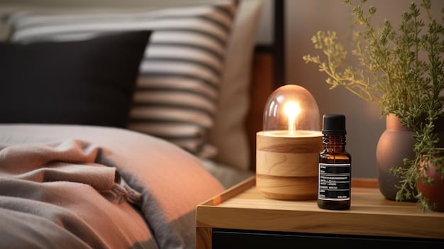 A close-up of an aromatherapy diffuser with essential oils, set on a wooden table next to a lit candle. Soft, ambient lighting enhances the calming atmosphere of the staycation space.