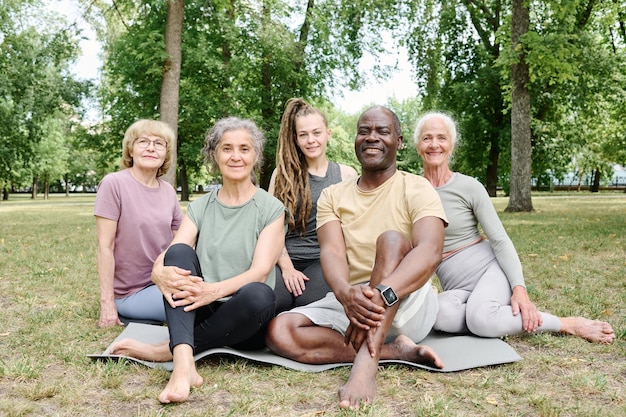 A diverse group of people meditating outdoors in a sunny park, with smiles on their faces and a sense of community.