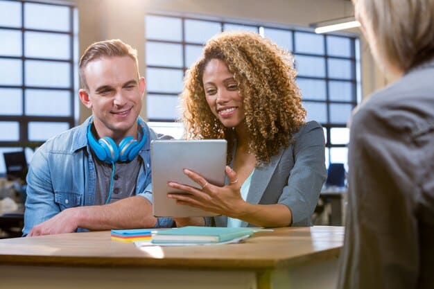 A college student participating in an informational interview with a professional in a modern office setting, both smiling and engaged in a discussion.