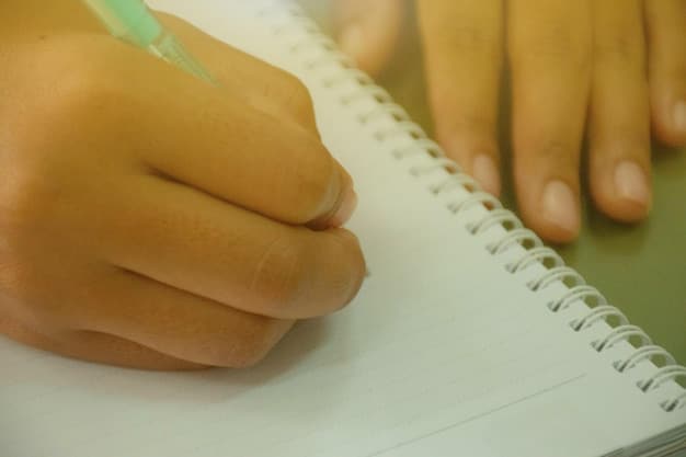 Close-up of a student's hand holding a pen, hovering over a notebook filled with brainstormed ideas and essay outlines. The background is blurred, emphasizing the creative process.