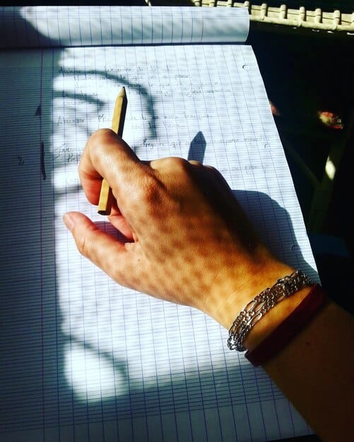 A detailed image showing a person meticulously writing notes in a notebook with a pen. The focus is on the hand and the notebook, creating a sense of focused evaluation.