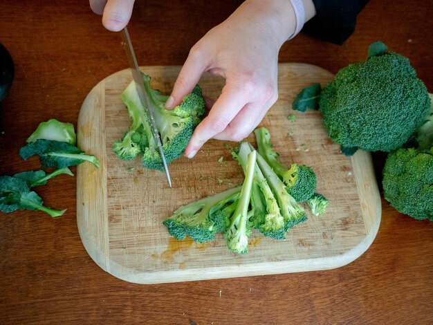 A close-up shot of a person preparing a dish using vegetable scraps, like broccoli stalks and carrot peels.